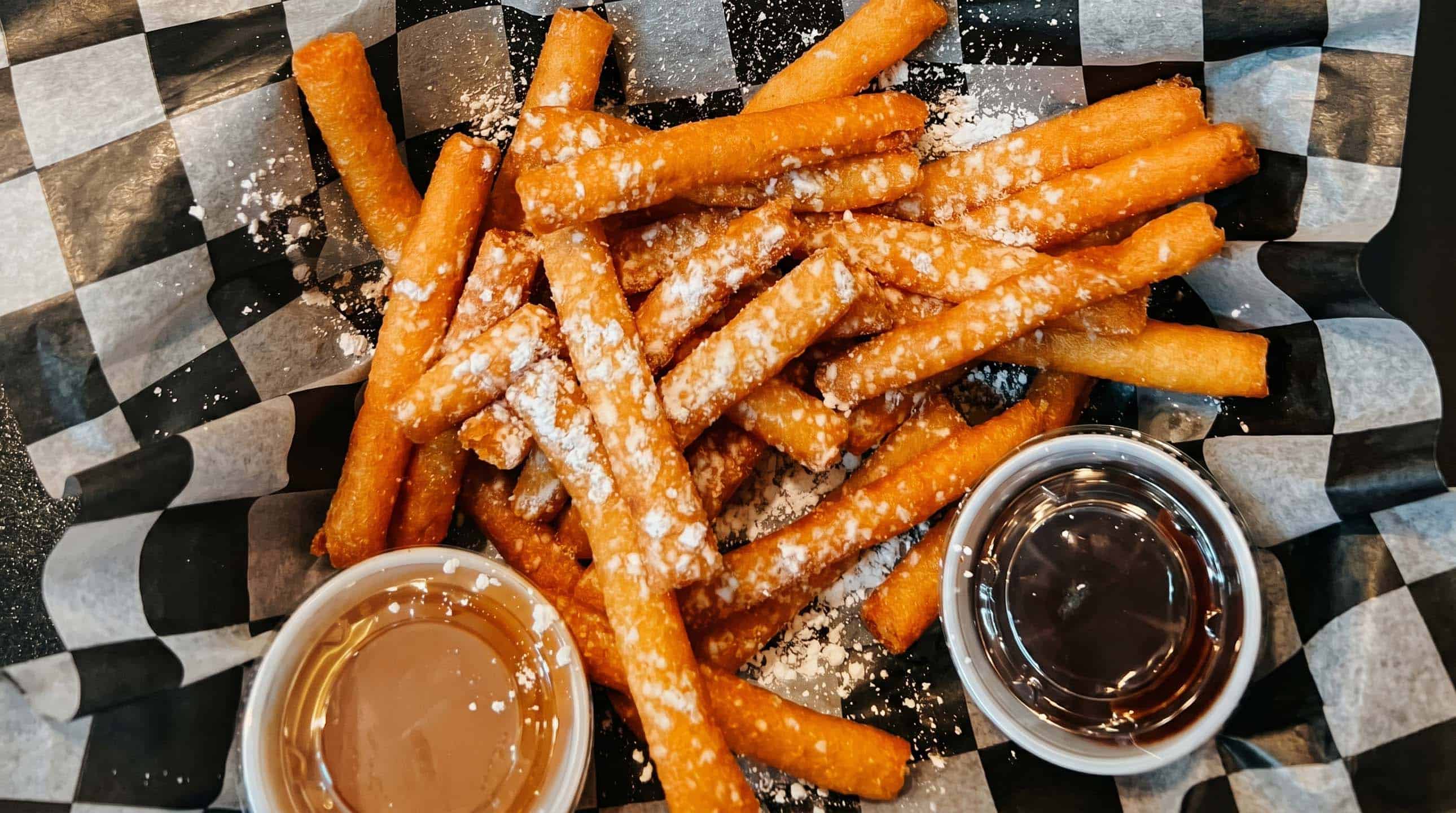 Funnel cake fries dusted with powdered sugar and dipping sauces